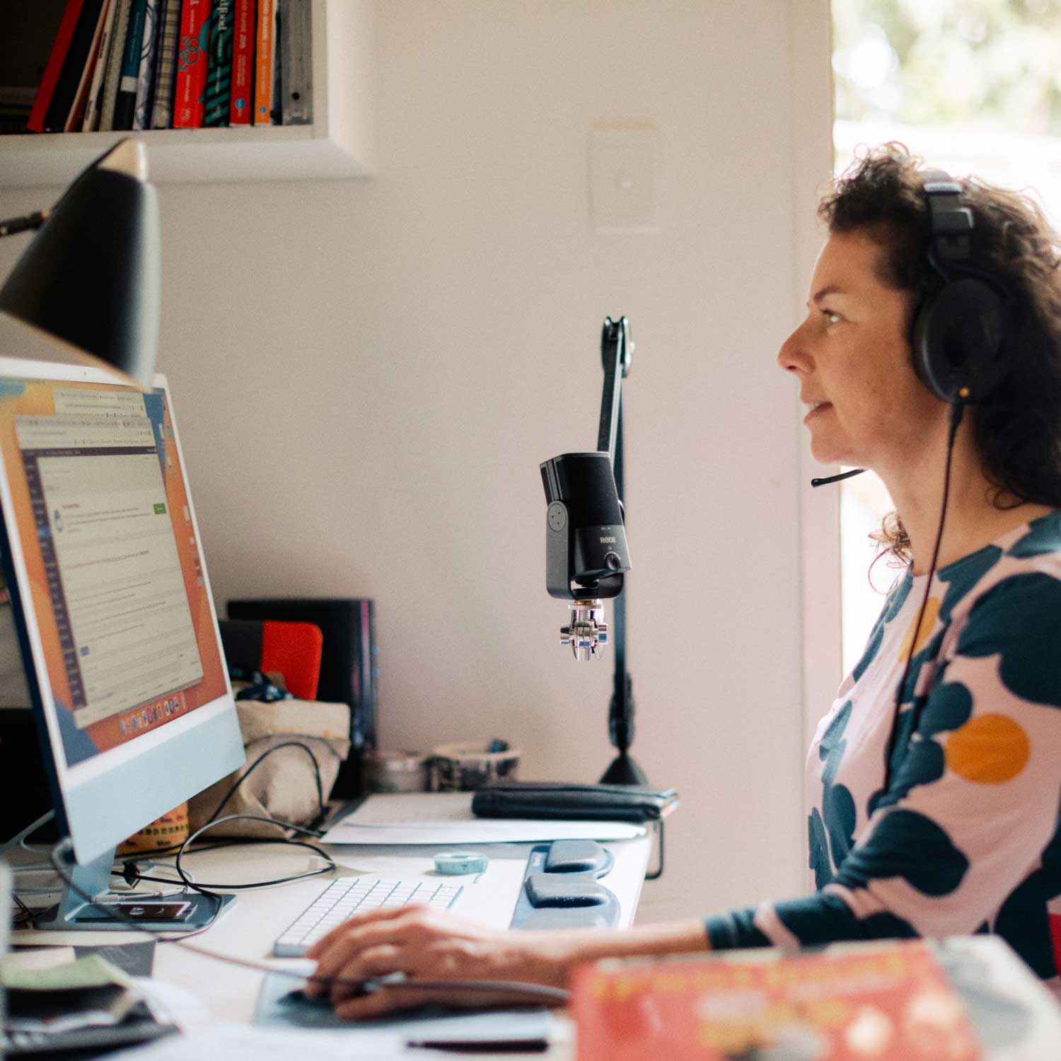 Dani Valent Podcast. photo of Dani at her desk microphone